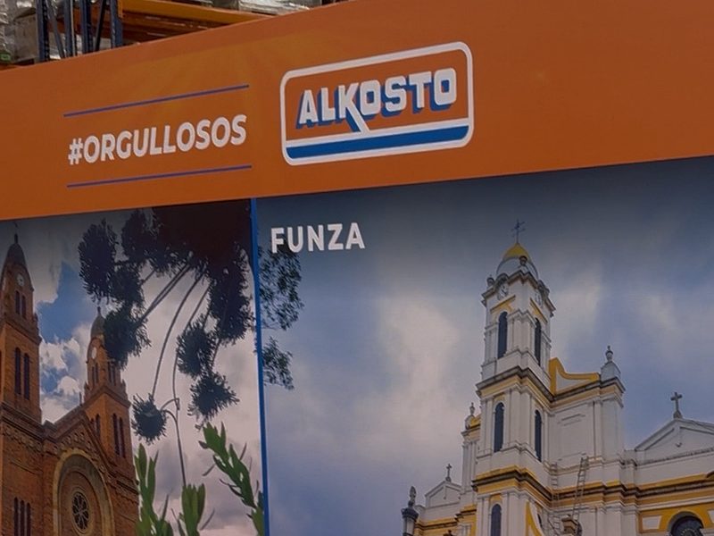 Backing naranja de gran formato con logo de marca, montado en punto de venta